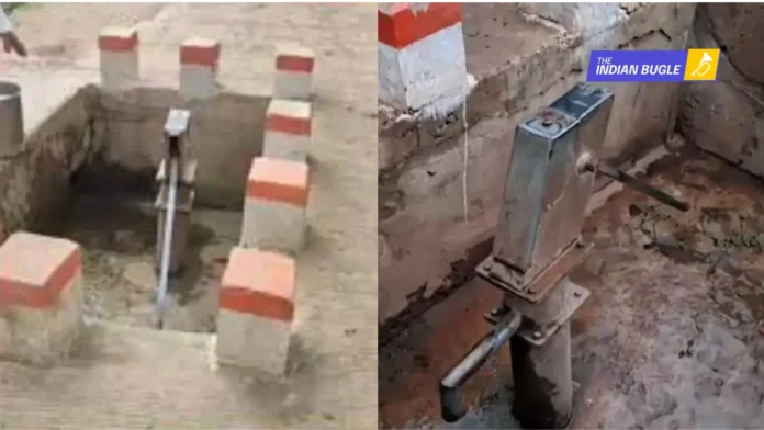 A newly constructed road has been paved around an active hand pump, instead of relocating it.